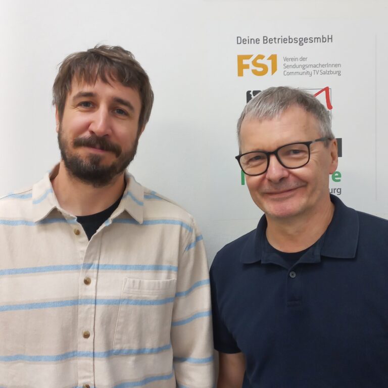 Ein Portraitfoto von Jonathan Zott und Wolfgang Descho vor der Logowand von FS1. Links im Bild steht Zott, neuer Gesch&auml;ftsf&uuml;hrer, rechts daneben der bisherige Gesch&auml;ftsf&uuml;hrer Descho. Beide blicken l&auml;chelnd direkt in die Kamera. Der Bildausschnitt zeigt beide Personen als Brustbild in legerer Arbeits-Kleidung.